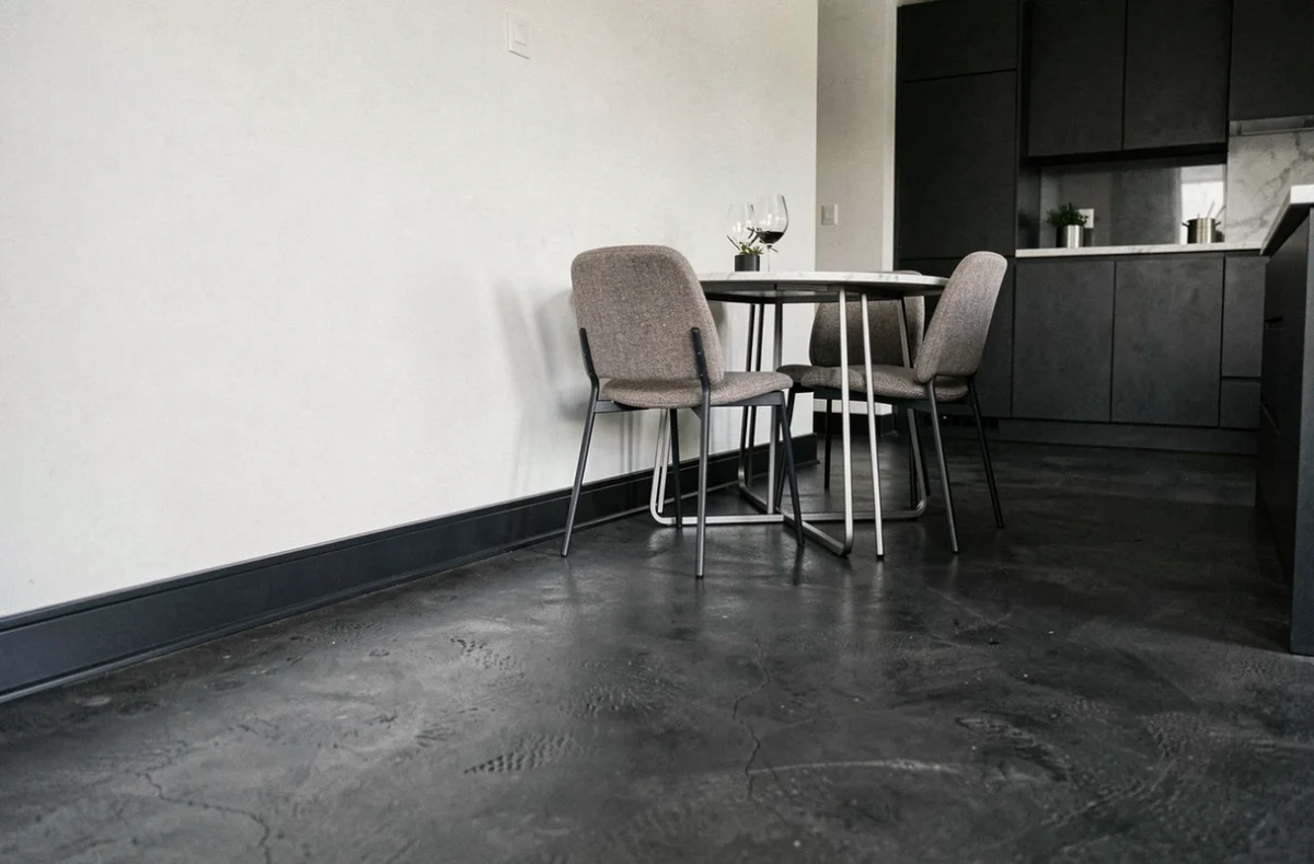 Plinthe en aluminium anthracite sur béton ciré foncé dans une cuisine contemporaine ouverte