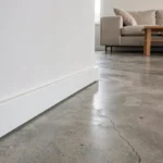 Plinthe blanche laquée sur sol en béton ciré dans un salon moderne minimaliste